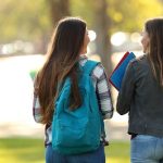 Back view of two students walking and talking