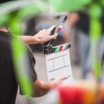 Man holding a clapperboard in front of the camera
